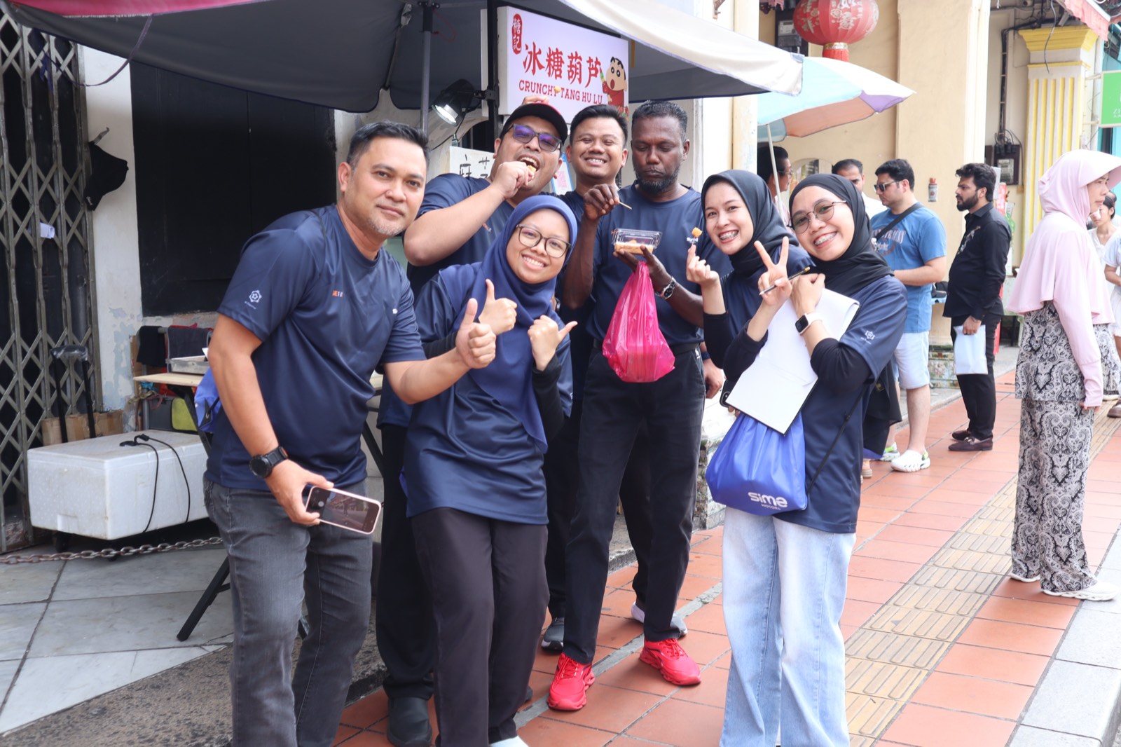 A team giving thumbs up at a street food stall during an Amazing Race activity