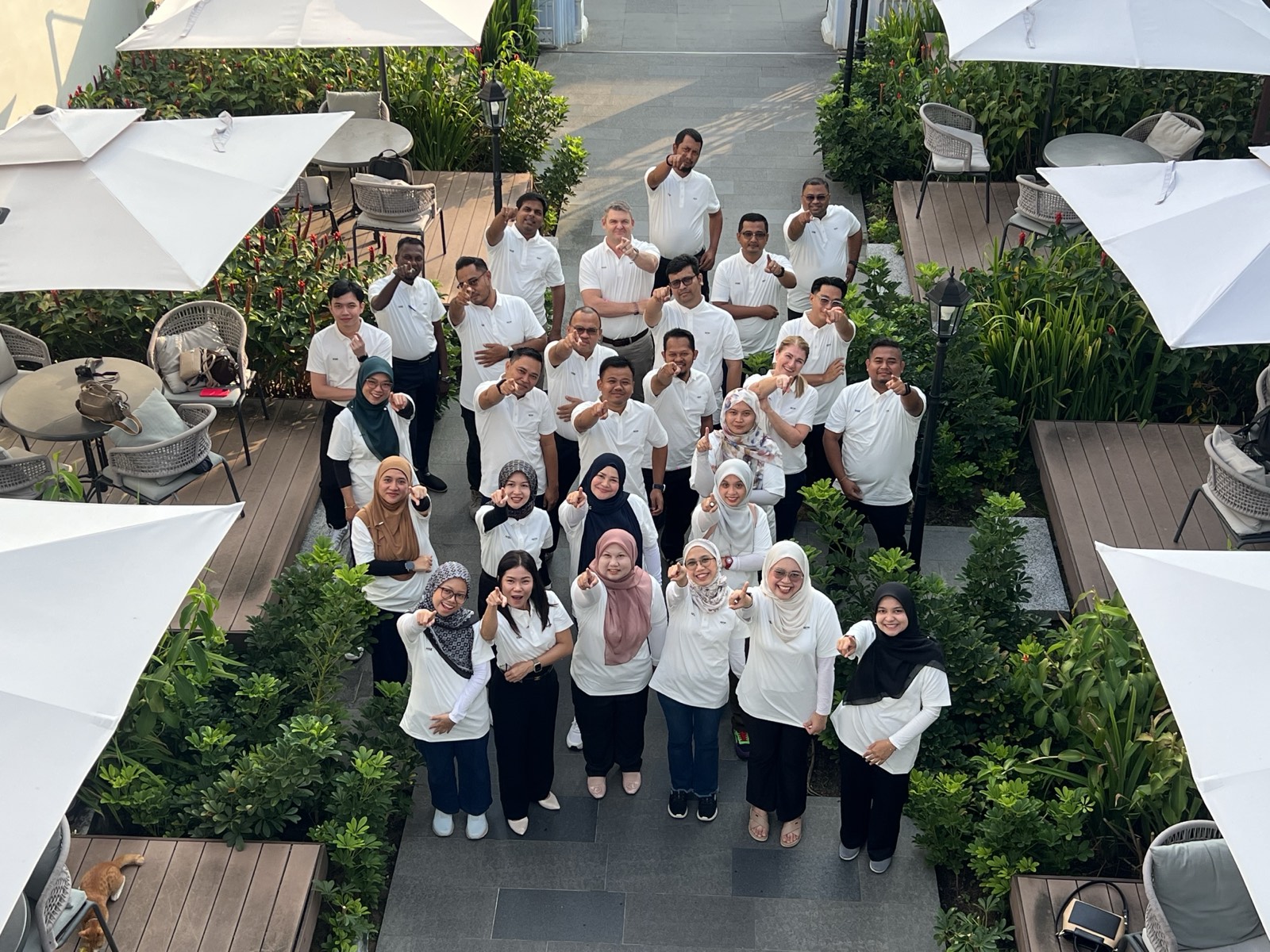 A large group of colleagues pointing at the camera and smiling
